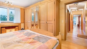 Ein Schlafzimmer mit einem Bett, einem Holzschrank und einem Fenster mit Vorhängen.
