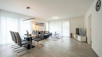 A modern living room with a dining area, a sofa set, and a television.