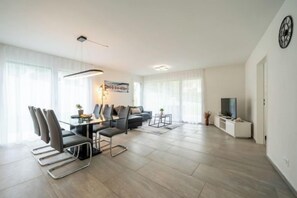 Una sala de estar moderna con comedor, un juego de sofá y un televisor.