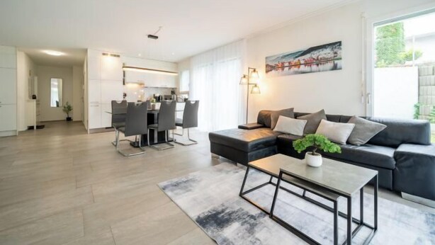 Una sala de estar moderna con sofá, mesa de centro y comedor.