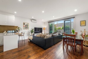 A modern living room with a sofa, dining table, and kitchen area.
