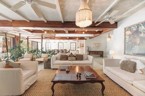 A spacious living area with a wooden coffee table, white sofas, and a chandelier. - Villa La Semilla • 5BR Beachfront w/ Chef (Tulum)