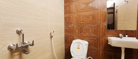 Un baño con un diseño de pared de madera, inodoro blanco, lavamanos y ducha con manguera.