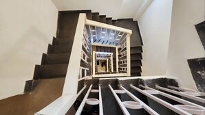 A staircase with a white railing, a skylight at the top, and a dark floor. - Golden Retreat Guest House (Kolkata)