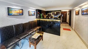 A lobby with a reception desk, a cushioned seating area, and artwork on the walls. - Golden Retreat Guest House (Kolkata)