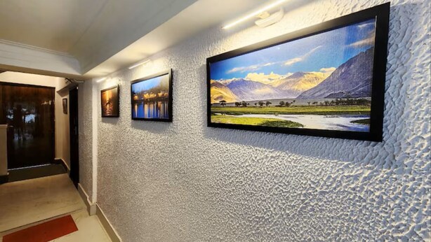 A hallway with textured walls, three framed pictures, and a red carpet. - Golden Retreat Guest House (Kolkata)