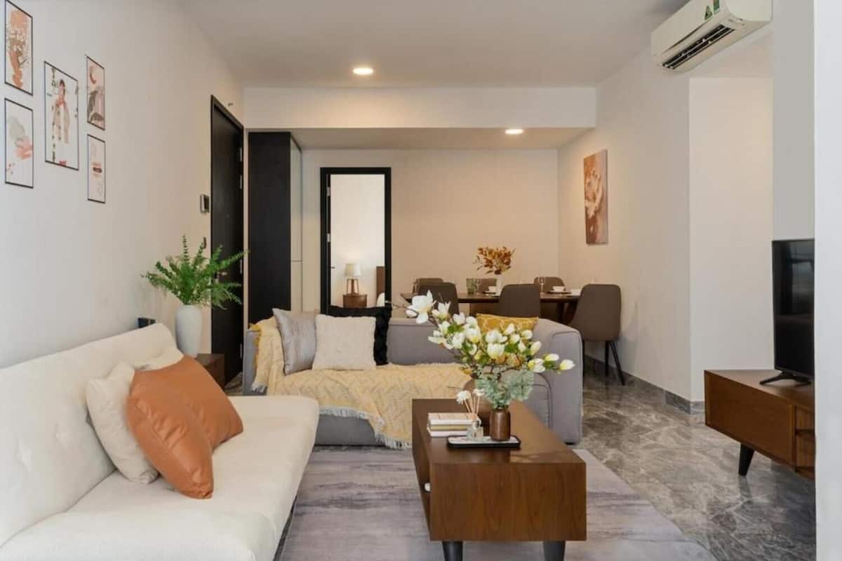 A modern living room with a sofa, coffee table, and a dining area with chairs and a table.