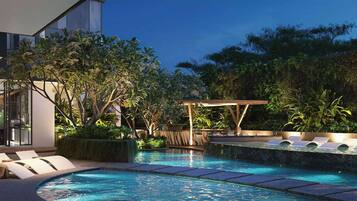 Una piscina al aire libre, sombrillas, sillones reclinables de piscina