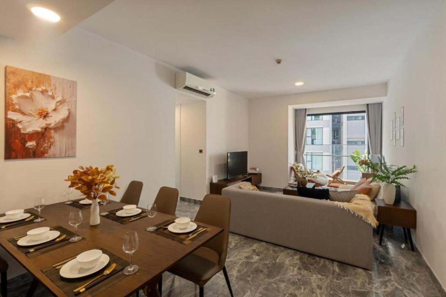 A modern dining area with a table set for four, a sofa, and a TV in the background.