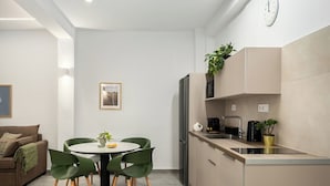 A modern kitchen with a refrigerator, microwave, and stove. There is a dining table with chairs and a plant on the counter.
