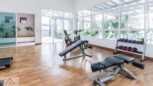 A spacious gym with exercise equipment, large windows, and a wooden floor. - Rumahku LRT, Ara Damansara, near Subang Airport (Petaling Jaya)