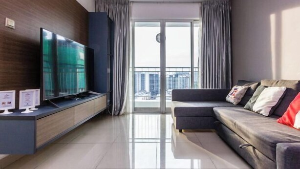 A modern living room with a flat-screen TV, a sofa, and a sliding glass door leading to a balcony. - Rumahku LRT, Ara Damansara, near Subang Airport (Petaling Jaya)