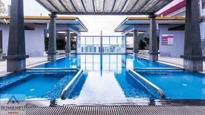 A swimming pool with a wooden pergola overhead, surrounded by stone pillars and a clear view of the city skyline. - Rumahku LRT, Ara Damansara, near Subang Airport (Petaling Jaya)