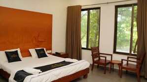 Une chambre d’hôtel avec un lit, un bureau, une chaise et de grandes fenêtres avec des rideaux.