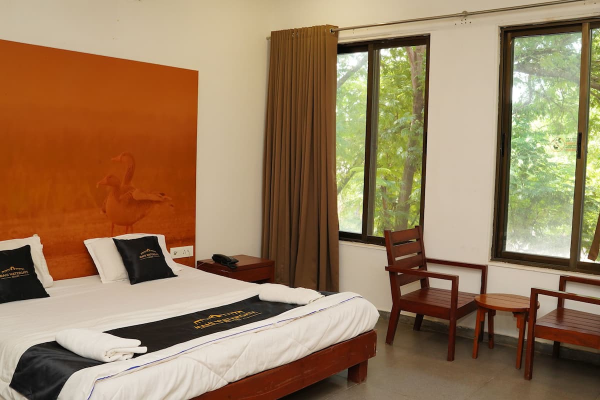 Une chambre d’hôtel avec un lit, un bureau, une chaise et de grandes fenêtres avec des rideaux.