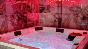 A hot tub with a marble wall backdrop and a neon sign.