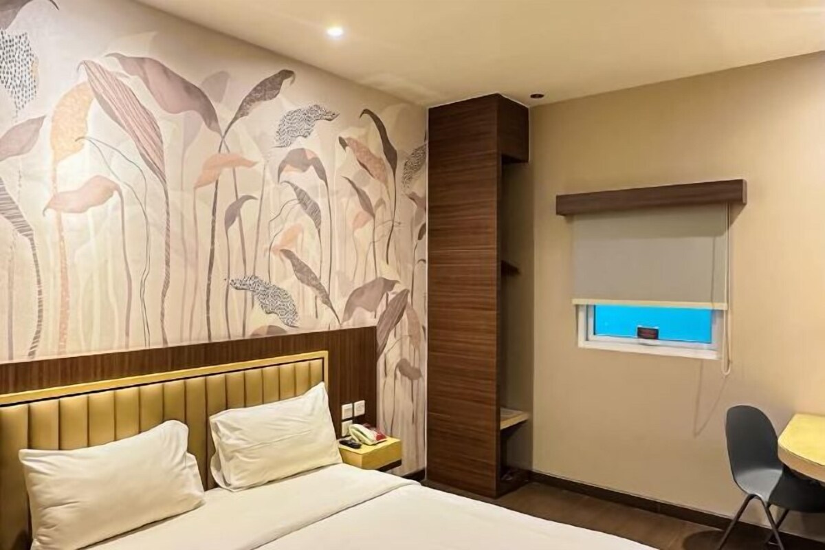 Une chambre d’hôtel comprenant un lit, une table de chevet, une chaise, une fenêtre avec vue et un mur décoratif.