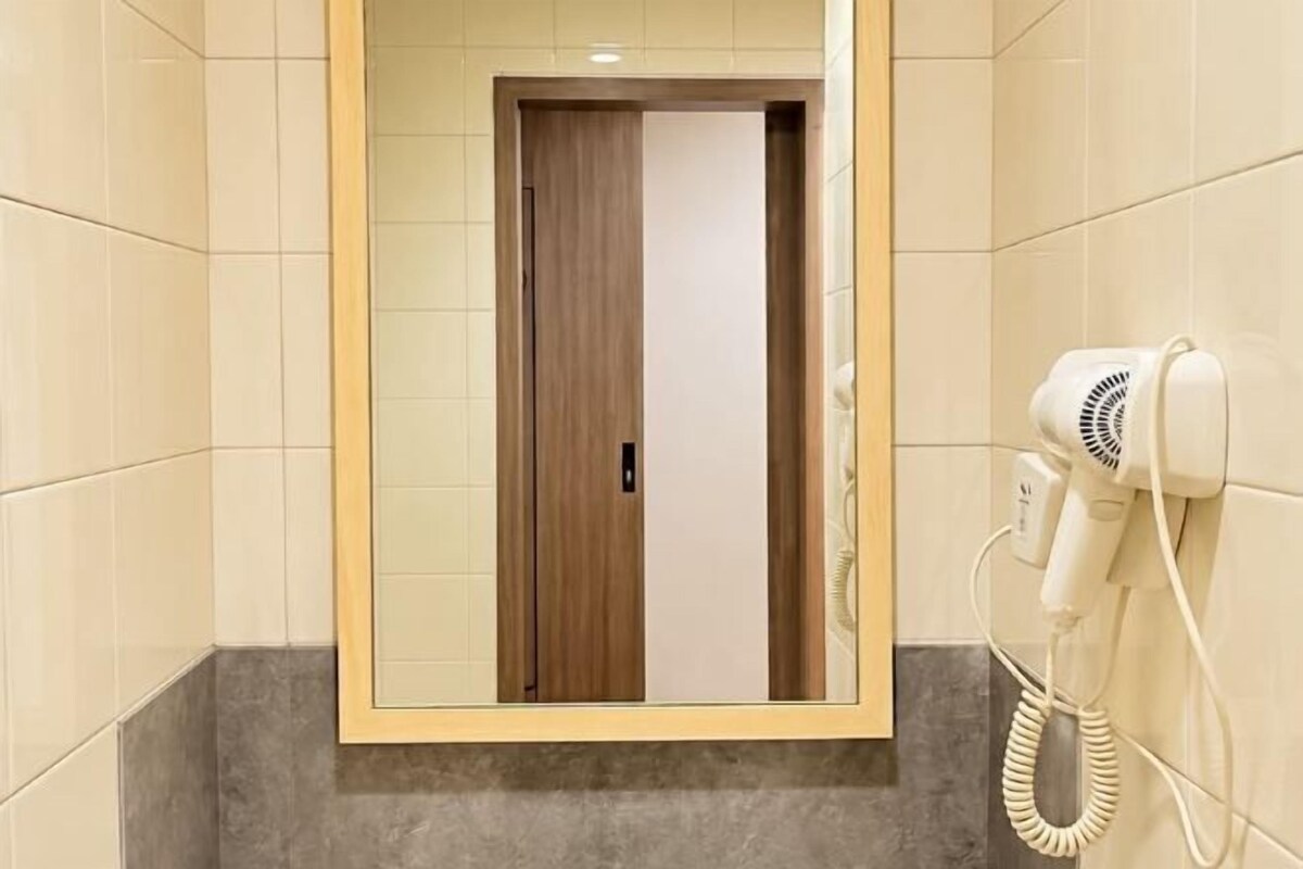Een hotelkamer met een deur, een haardroger op de muur en een marmeren vloer.