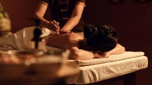 Een massage in een kamer met weinig licht, met een massagetafel en iemand die een rugmassage ontvangt.