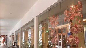 Een hotel met een glazen gevel, decoratieve bloemmotieven en Chinese karakters.