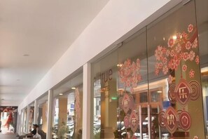 Een hotel met een glazen gevel, decoratieve bloemmotieven en Chinese karakters.