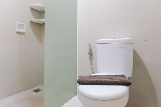 A bathroom with a toilet, a shower, and a towel rack.