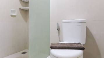 A bathroom with a toilet, a shower, and a towel rack.