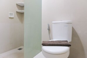 A bathroom with a toilet, a shower, and a towel rack. - Gala by TwoSpaces Studio @TreePark Apartment (Serpong)
