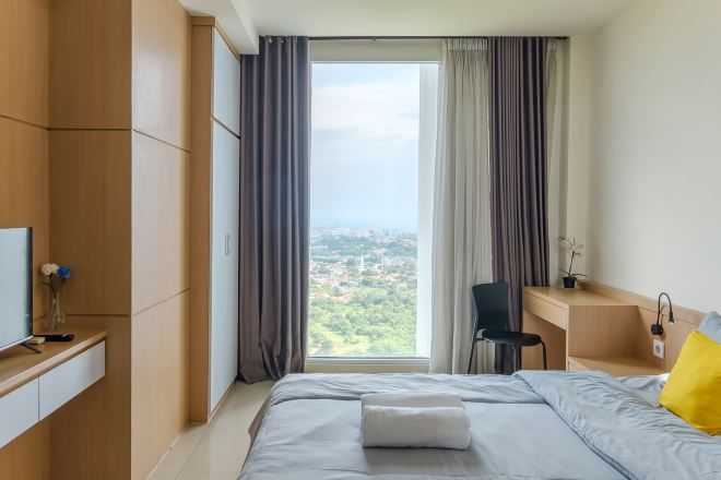 A modern hotel room with a large bed, a desk, and a chair.