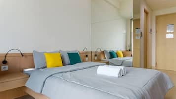 A hotel room with a bed, bedside tables, a mirror, and a door.