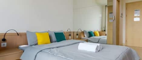 A hotel room with a bed, bedside tables, a mirror, and a door.
