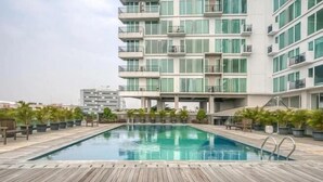 A modern hotel with a rooftop pool, surrounded by potted plants and wooden deck. - Gala by TwoSpaces Studio @TreePark Apartment (Serpong)