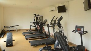 A gym with treadmills, elliptical machines, and a stationary bike. - Gala by TwoSpaces Studio @TreePark Apartment (Serpong)