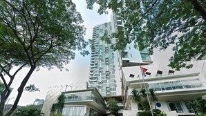 A modern building with a staircase leading to the entrance, surrounded by greenery and a flag. - Gala by TwoSpaces Studio @TreePark Apartment (Serpong)