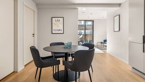 Un comedor moderno con una mesa redonda, cuatro sillas y una obra de arte enmarcada en la pared.