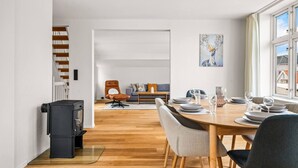 Een moderne woonkamer met een eethoek, een open haard en uitzicht op buiten.