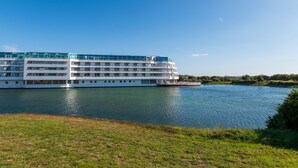 A large, multi-story riverboat with a white exterior and blue upper deck, docked at a calm river. - Studio L'Océanic, summer pool, near beach and port, parking, towels & cleaning extra (Arzon)