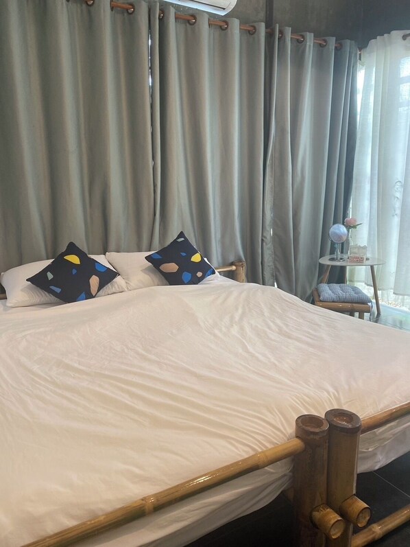 A bed with a white sheet, two pillows with a polka dot pattern, and a wooden headboard. - Baaninkan (Ban Tai)