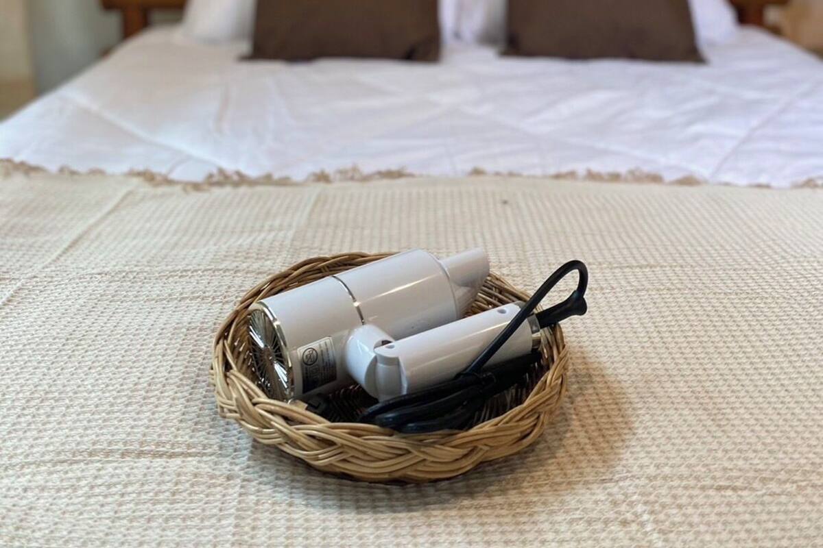 Una cama bien tendida con una colcha blanca y marrón, una cesta de mimbre con dos platos blancos sobre una superficie texturizada.
