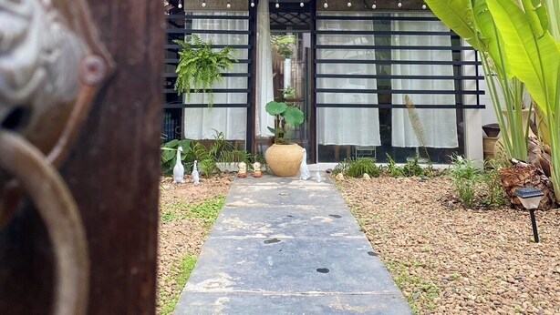 A pathway leading to a building with a tiled roof and large windows. - Baaninkan (Ban Tai)