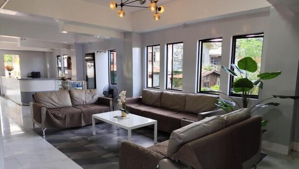 Ein modernes Wohnzimmer mit einer Sofagarnitur, einem Couchtisch und großen Fenstern mit Blick ins Freie.