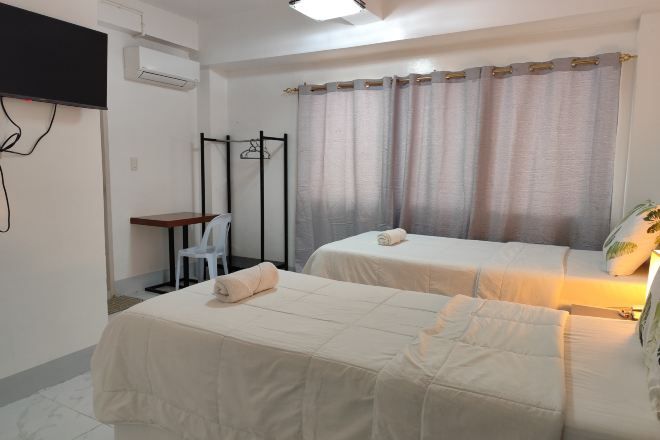 A hotel room with two beds, a desk, a chair, and a window with curtains.