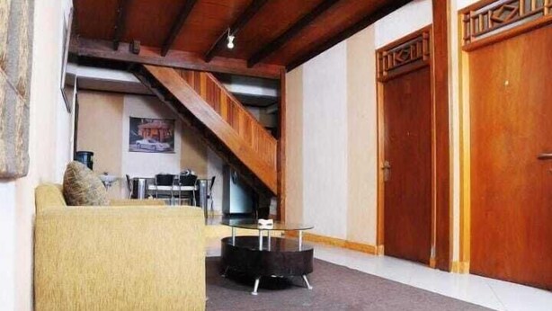 A cozy living room with a sofa, a round coffee table, and a staircase leading to an upper level. - Jatimas Hijau Hotel & Villa (Cisarua)