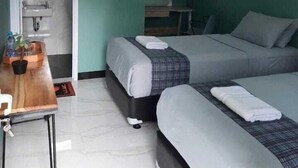 Una stanza con due letti, un tavolino con una pianta, una finestra e una porta che dà su un bagno.