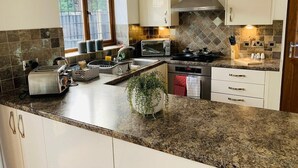 A modern kitchen with granite countertops, stainless steel appliances, and white cabinetry. - Wakefield 3 Bed Home (West Yorkshire)