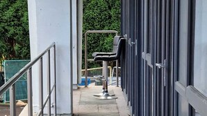 A covered outdoor walkway with metal railings, leading to a building with large windows. - Home Away From Home (Brierley Hill)