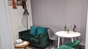 A compact living space with a green sofa, a small round table, and a green chair. - Home Away From Home (Brierley Hill)