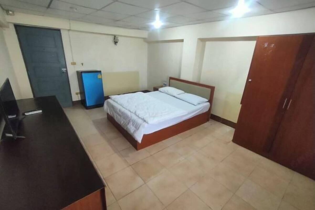 Une chambre avec un lit, un bureau, une armoire et un meuble bleu.