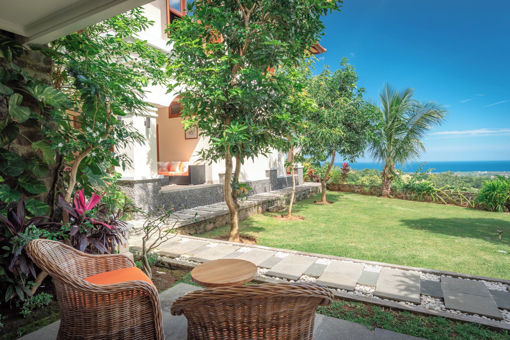 A patio with wicker furniture, a stone pathway, and a view of the ocean.