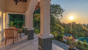 A covered outdoor seating area with stone pillars, a table, and chairs. - Villa Mata Hari (Sukasada)